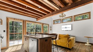 Una cocina con una isla central, vigas de madera en el techo y ventanas amplias.