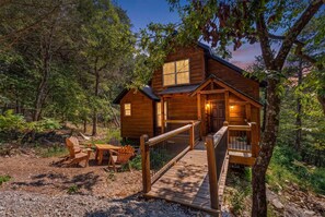 A wooden cabin with a deck, seating area, and a number '1250' on the front. - Cozy Cabin_Peaceful Wooded Views_Free Attraction Tickets_Deck Space (Branson)