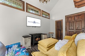 Ein gemütliches Wohnzimmer mit Kamin, einem an der Wand befestigten Fernseher und einer großen Holztür.