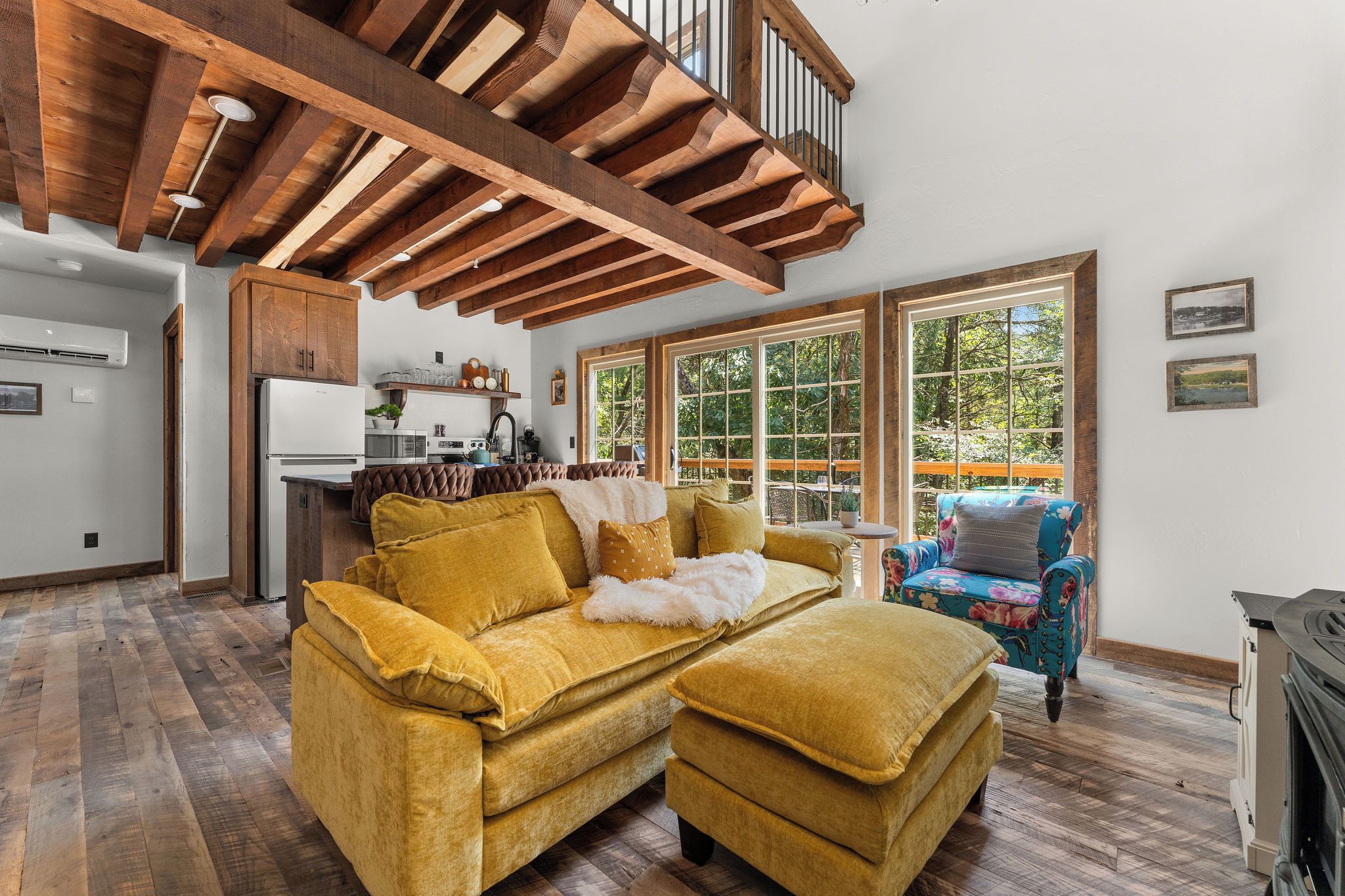 A spacious living area with a wooden ceiling, a sofa set, a fireplace, and large windows.