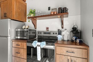 Een praktische keuken met een koelkast, magnetron, fornuis en houten kastjes.