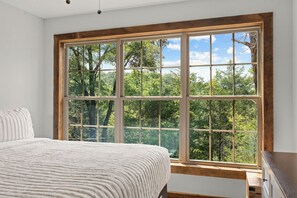 A bedroom with a large window, a bed, and a dresser. - Cozy Cabin Tucked Away w Free Attraction Tickets_Deck Space_Bonus Loft_Near Branson (Branson)