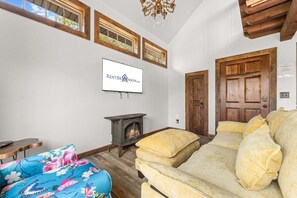 Ein Wohnzimmer mit Kamin, einer Couch, einem Fernseher und einer Tür.