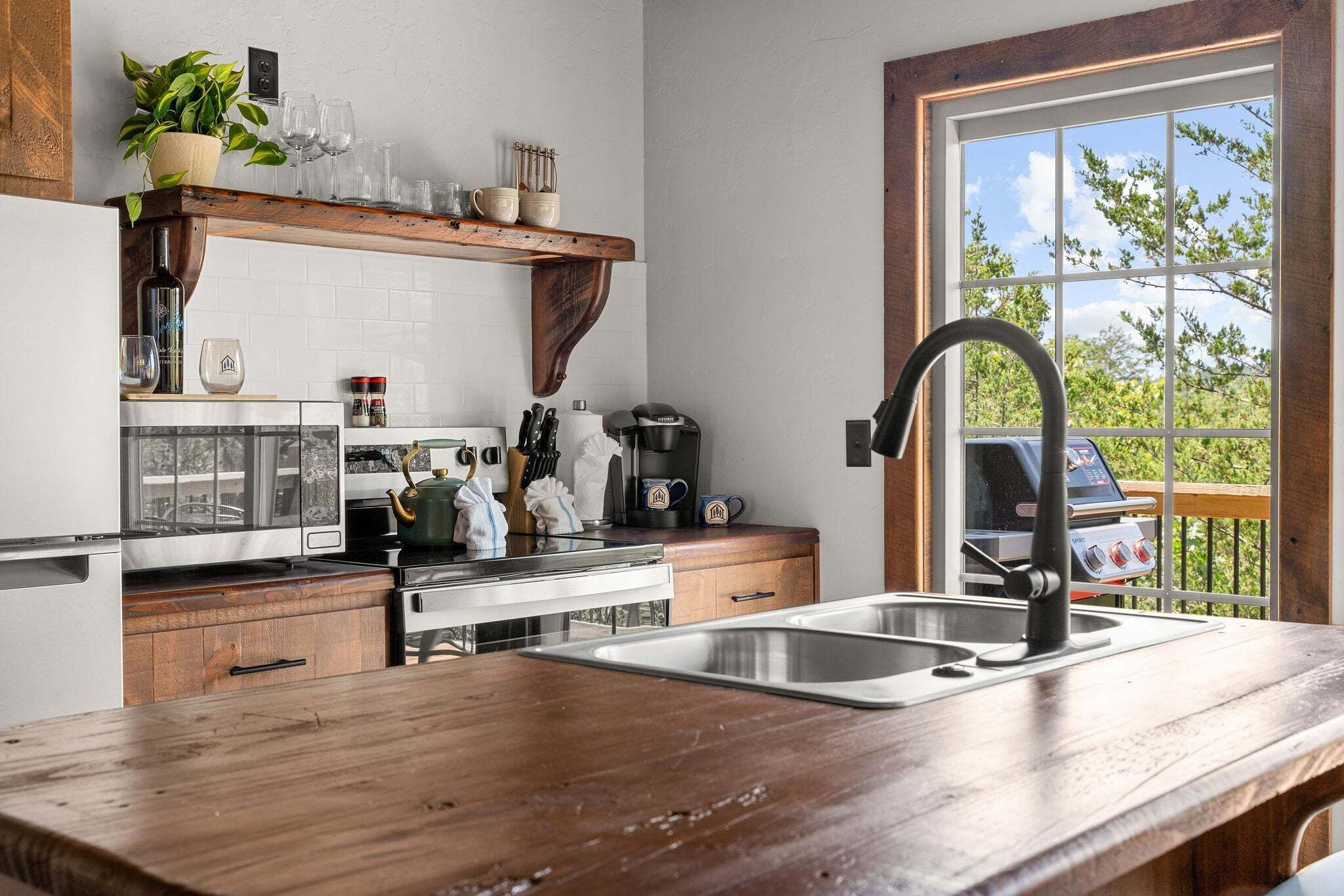 A kitchen with a wooden countertop, stainless steel sink, and a coffee maker.