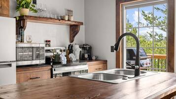 A kitchen with a wooden countertop, stainless steel sink, and a coffee maker.