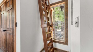Eine Holztür mit Metallbeschlag, ein Fenster mit Blick auf Bäume und ein an der Wand befestigter Lichtschalter.