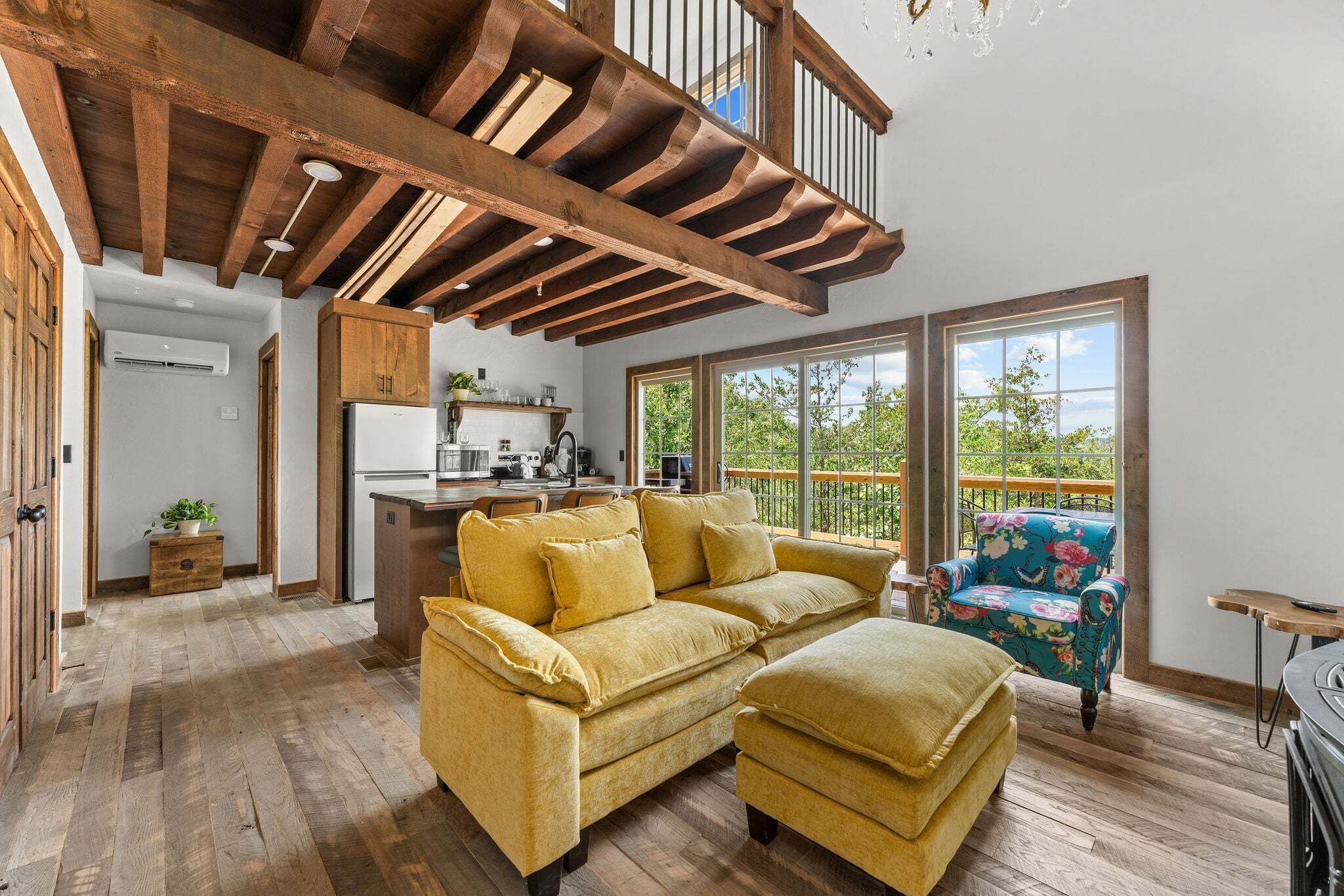 Un'ampia zona giorno con soffitto in legno, divani, un tavolo da pranzo e un balcone con vista.