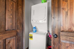 A laundry room with a white washing machine, a blue detergent bottle, and a red mop. - Tucked Away Cabin w Peaceful Views_Near Branson_Free Attraction Tickets (Branson)