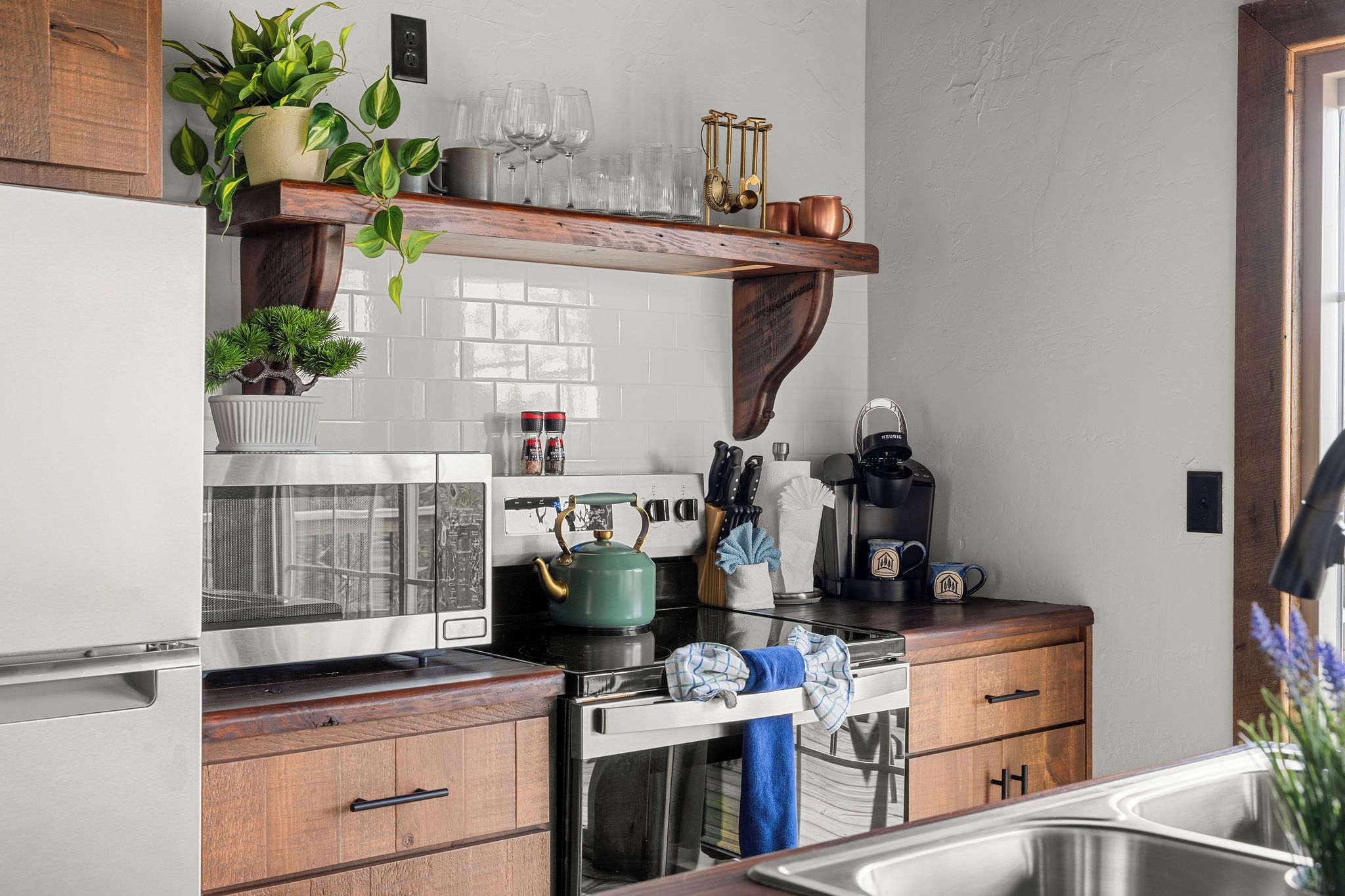 Una cocina equipada con microondas, hervidor, cafetera y diversos utensilios.