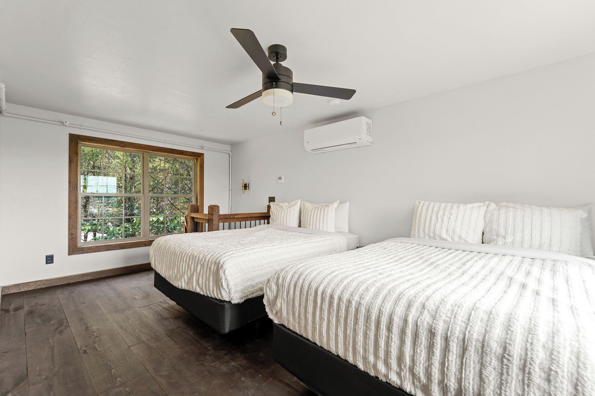 A bedroom with two beds, a ceiling fan, an air conditioning unit, and a large window.