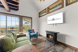 Ein gemütliches Wohnzimmer mit Kamin, einer Couch, einem Sessel und einem an der Wand befestigten Fernseher.