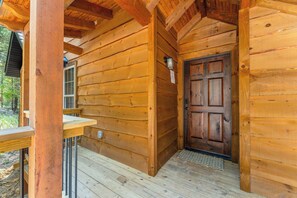 Eine Holzhütte mit Veranda, einer Tür und einem kleinen Fenster.