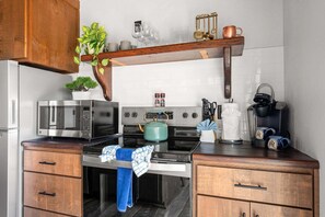 Eine moderne Küche mit Edelstahlgeräten, Holzschränken und einer hängenden Pflanze.