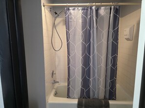 Bañera con ducha, toallas, jabón, shampoo