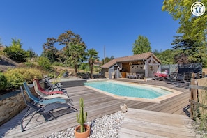 A wooden deck with a pool, outdoor seating, and a small building with a tiled roof. - Gîte des Sources - CUISERY (CUISERY)