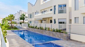 Un immeuble résidentiel moderne doté d’une piscine, de balcons et d’une entrée sécurisée.