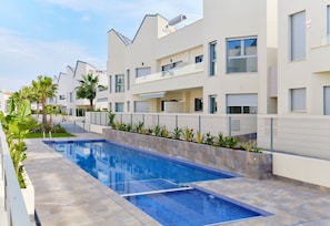 A modern residential building with a swimming pool, balconies, and a gated entrance. - Villa Amalia 9: Ground floor with garden (Torrevieja)
