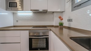 Une cuisine moderne avec des meubles blancs, un four en acier inoxydable, un micro-ondes et un évier.