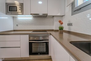 A modern kitchen with white cabinetry, a stainless steel oven, a microwave, and a sink. - Villa Amalia 9: Ground floor with garden (Torrevieja)