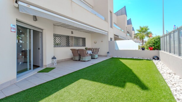 Un bâtiment moderne doté d’un patio couvert, d’un espace extérieur aménagé pour s’asseoir et d’une pelouse bien entretenue.