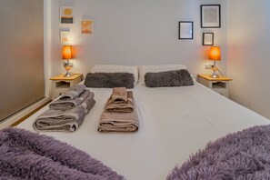 A hotel room with a bed, two pillows, a bedside table with a lamp, and a wall with framed pictures. - Villa Amalia 9: Ground floor with garden (Torrevieja)