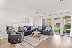 A living room with a sectional sofa, a leather armchair, a coffee table, and a ceiling fan. - CLM 4A Lovely Destin Chateau Unit - Private Beach Access (Destin)