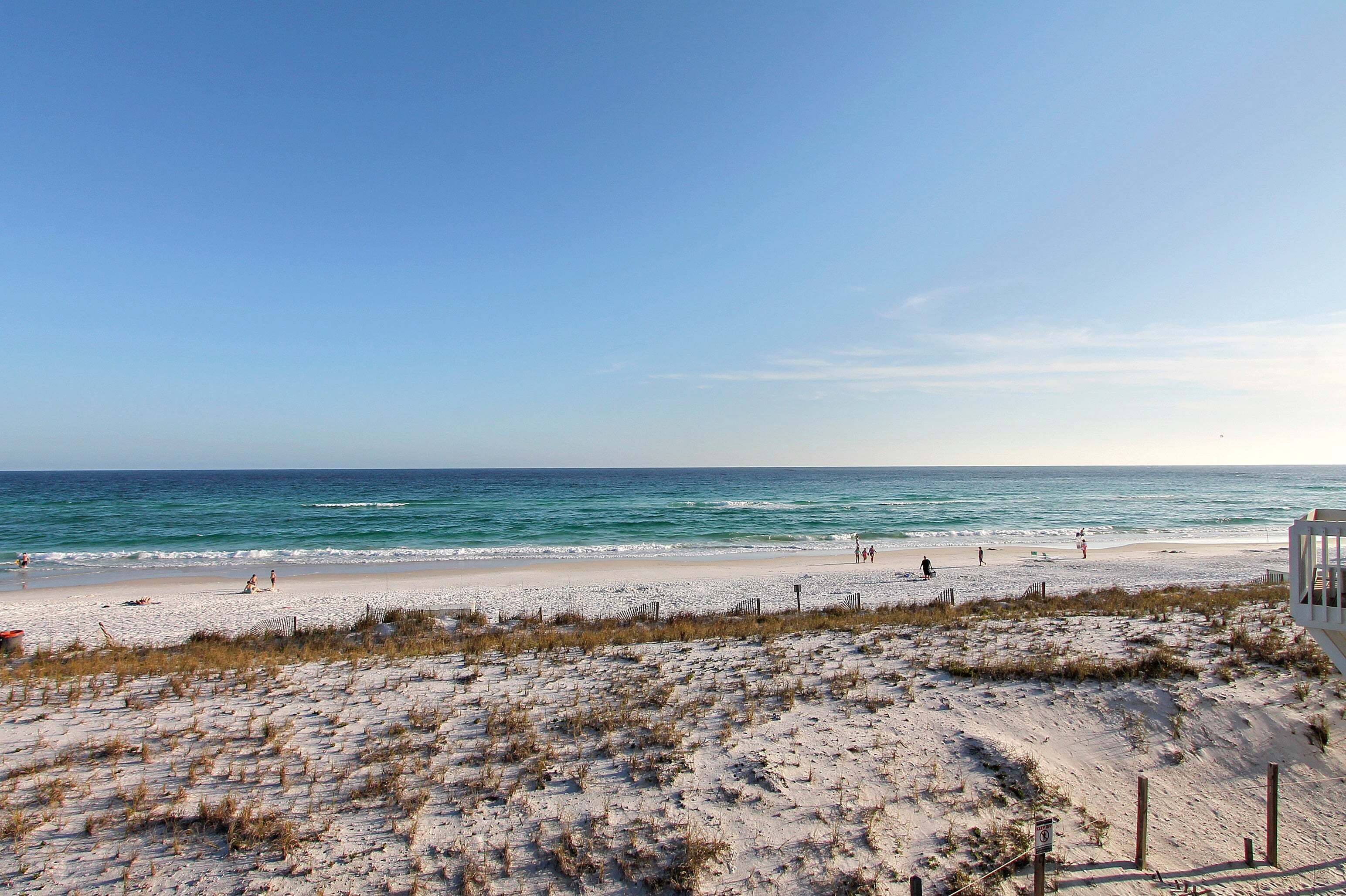 A beach with a clear sky, sandy shore, and a lifeguard tower.