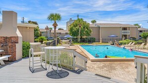 A pool area with a wooden deck, lounge chairs, and a brick barbecue. - CLM 16B  Gorgeous, pet friendly - Private beach access (Destin)