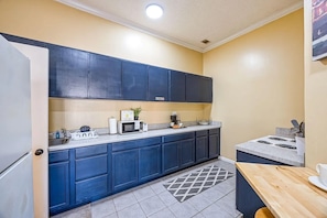 A compact kitchen with dark blue cabinets, a microwave, a coffee maker, and a small sink.