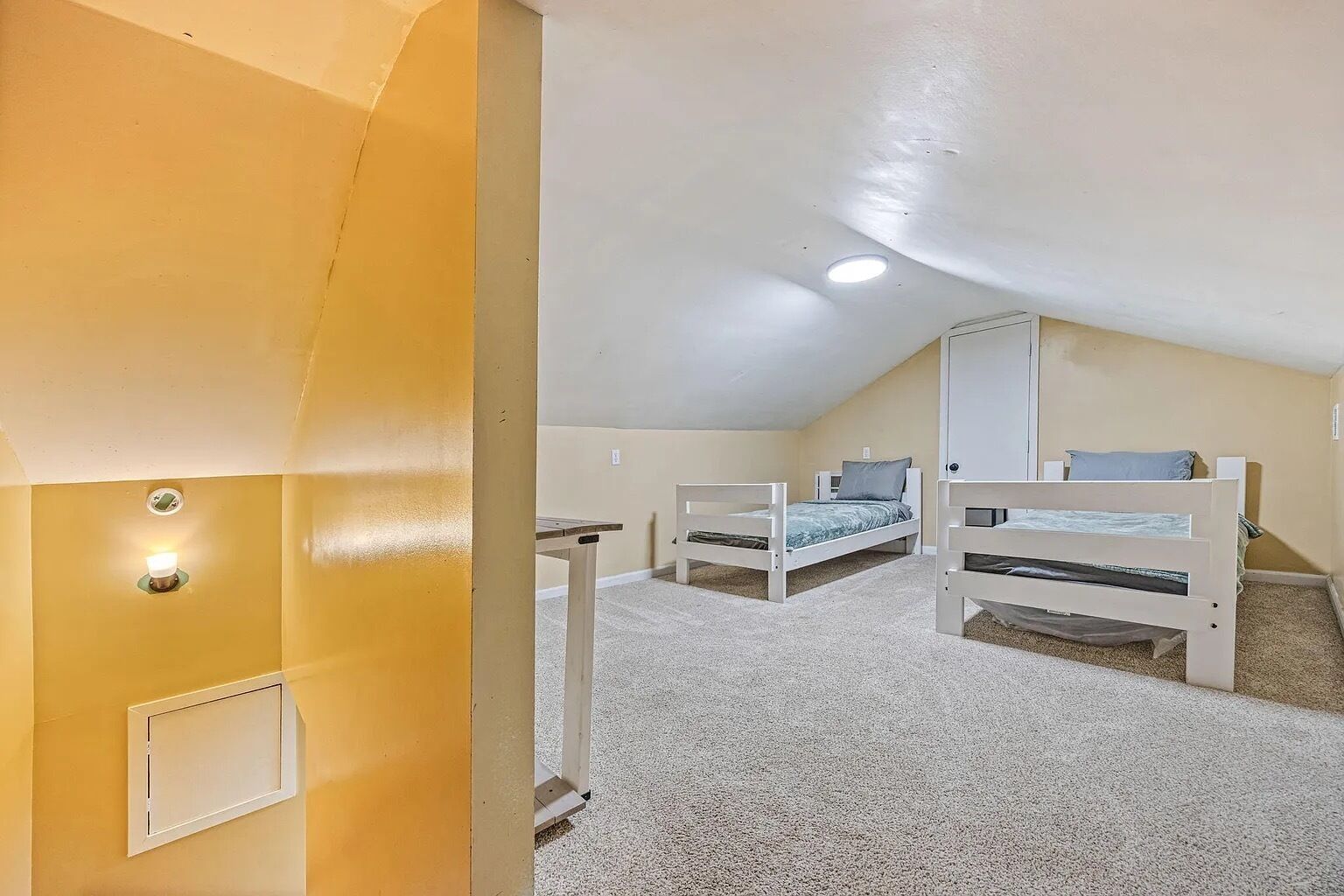 Une pièce avec deux lits superposés, une petite table et un luminaire au plafond.
