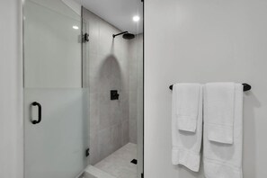 A modern bathroom with a glass shower enclosure, a towel rack with two white towels, and a visible shower control panel. - Cozy 1-bedroom studio in lovely Miami (Miami)