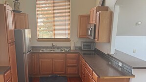 Eine Küche mit Holzausstattung, einem Edelstahlkühlschrank, einer Mikrowelle und einem eingebauten Backofen.