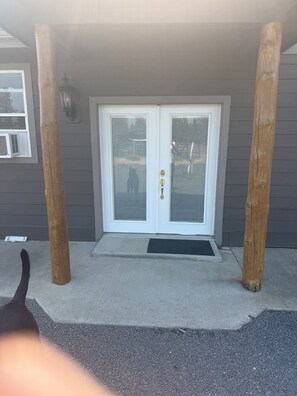 A double door entrance with a doormat, wooden posts, and a window with blinds. - Charming 2-bedroom building in peaceful Spangle with AC (Spangle)