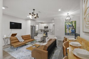 A modern living room with a sofa, coffee table, and dining area with a table set for two.