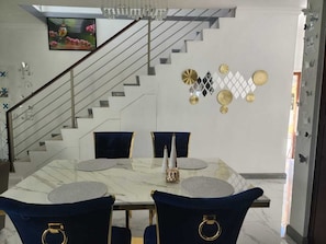 A dining area with a marble table, dark blue chairs, and a staircase in the background. - 3 Bedroom Luxe Hideaway in Ocho Rios with Pool Access (Ocho Rios)
