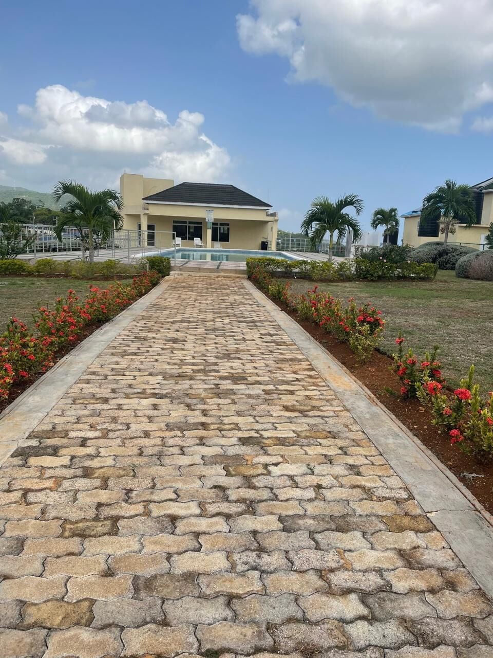 A paved pathway leading to a building with a flat roof and a covered entrance.