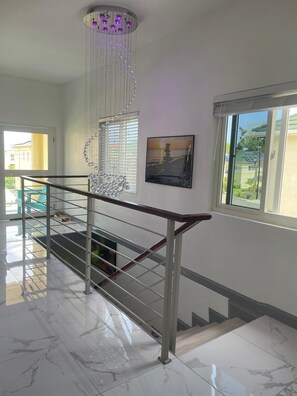 Eine Treppe mit Glastrennwand, einem Chandelier und einem Gemälde an der Wand.