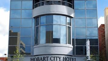 A modern building with a curved glass facade, a prominent entrance, and a sign reading 'HOBART CITY HOTEL'.