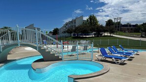 Ein Pool mit geschwungener Form, einem verschlossenen Eingang und blauen Liegestühlen am Beckenrand.