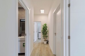 A hallway with a potted plant, a door, and a visible bathroom with a bathtub. - Bela House, By Home Match (Setúbal)