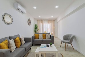 A modern living room with a grey sofa, a matching armchair, a coffee table, and a dining area in the background. - Bela House, By Home Match (Setúbal)