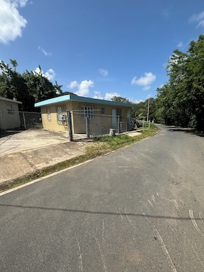 A paved road with a fenced area and a small building with a blue roof.