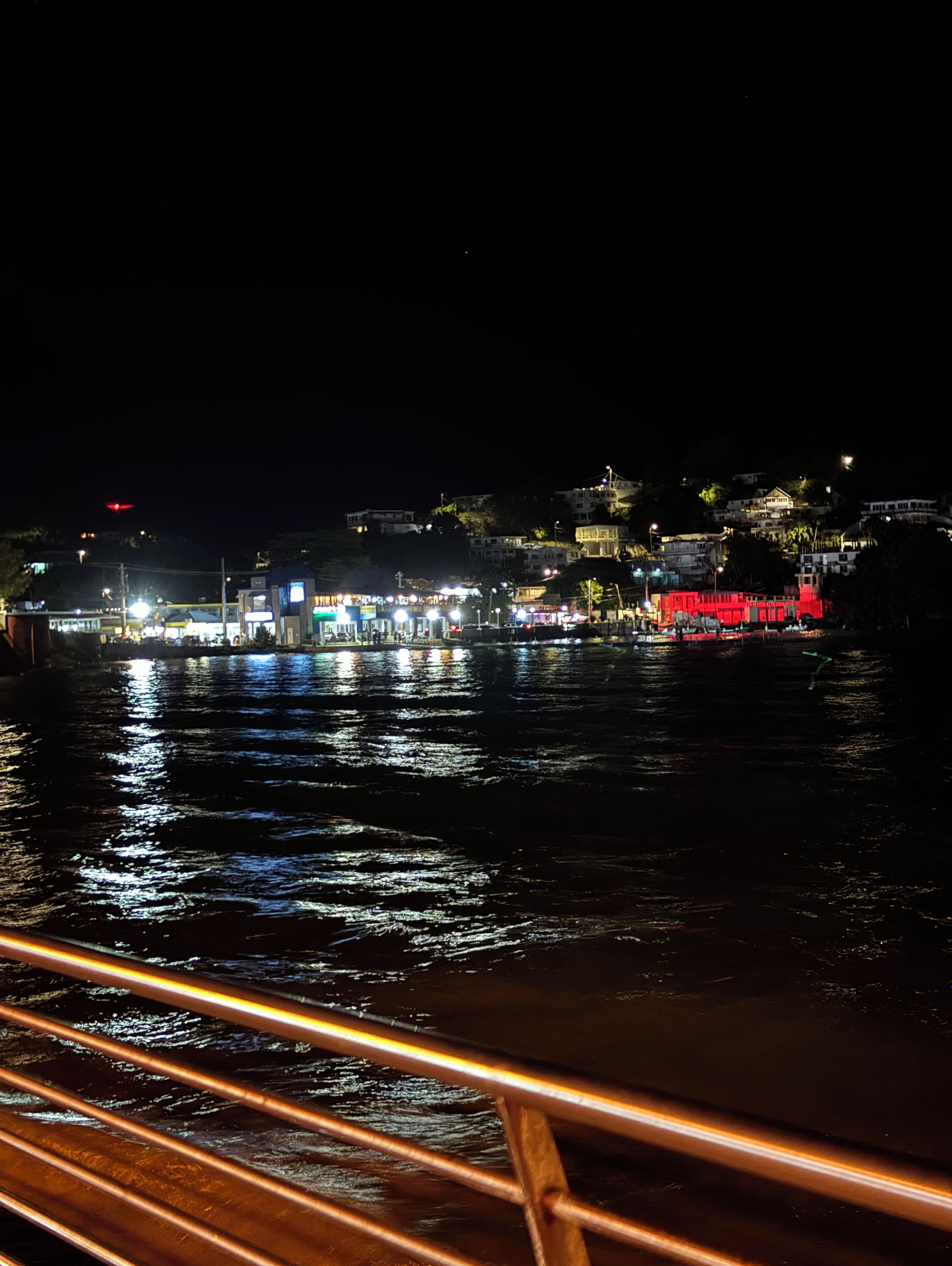 Une vue nocturne d’une zone riveraine, avec des bâtiments et un pont.