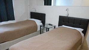 Two single beds with headboards, a small table, and a mirror above the beds. - Twin room hobart central (Hobart)