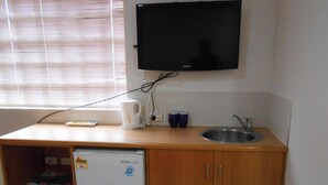 A kitchenette with a built-in microwave, a sink, and a flat-screen TV mounted on the wall. - Twin room hobart central (Hobart)