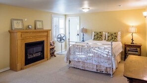 A bedroom with a bed, a fireplace, a fan, and a lamp. - The Cottage at Capitol Hill by Avantstay Group Retreat + Yard Walk to Paso (Paso Robles)