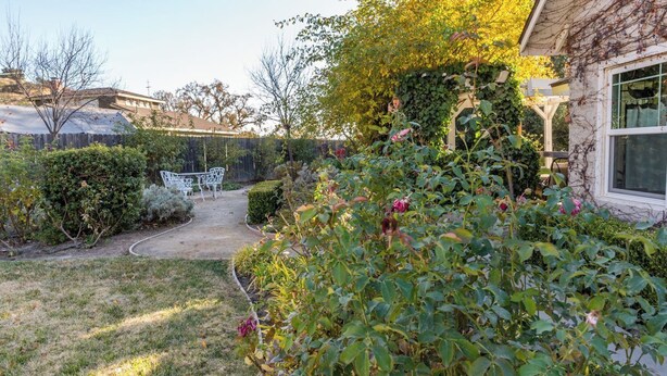 A garden with a pathway leading to a white bench, surrounded by various plants and a wooden pergola. - The Cottage at Capitol Hill by Avantstay Group Retreat + Yard Walk to Paso (Paso Robles)