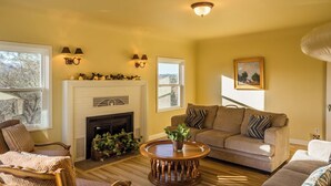 A living room with a fireplace, a sofa, a chair, and a coffee table. - The Cottage at Capitol Hill by Avantstay Group Retreat + Yard Walk to Paso (Paso Robles)