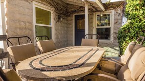 A round outdoor table with a mosaic tile design, surrounded by beige cushioned chairs. - The Cottage at Capitol Hill by Avantstay Group Retreat + Yard Walk to Paso (Paso Robles)