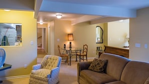 A living room with a sofa, armchair, and a dining table with chairs. There is a mirror on the wall and a fan on a stand. - The Cottage at Capitol Hill by Avantstay Group Retreat + Yard Walk to Paso (Paso Robles)